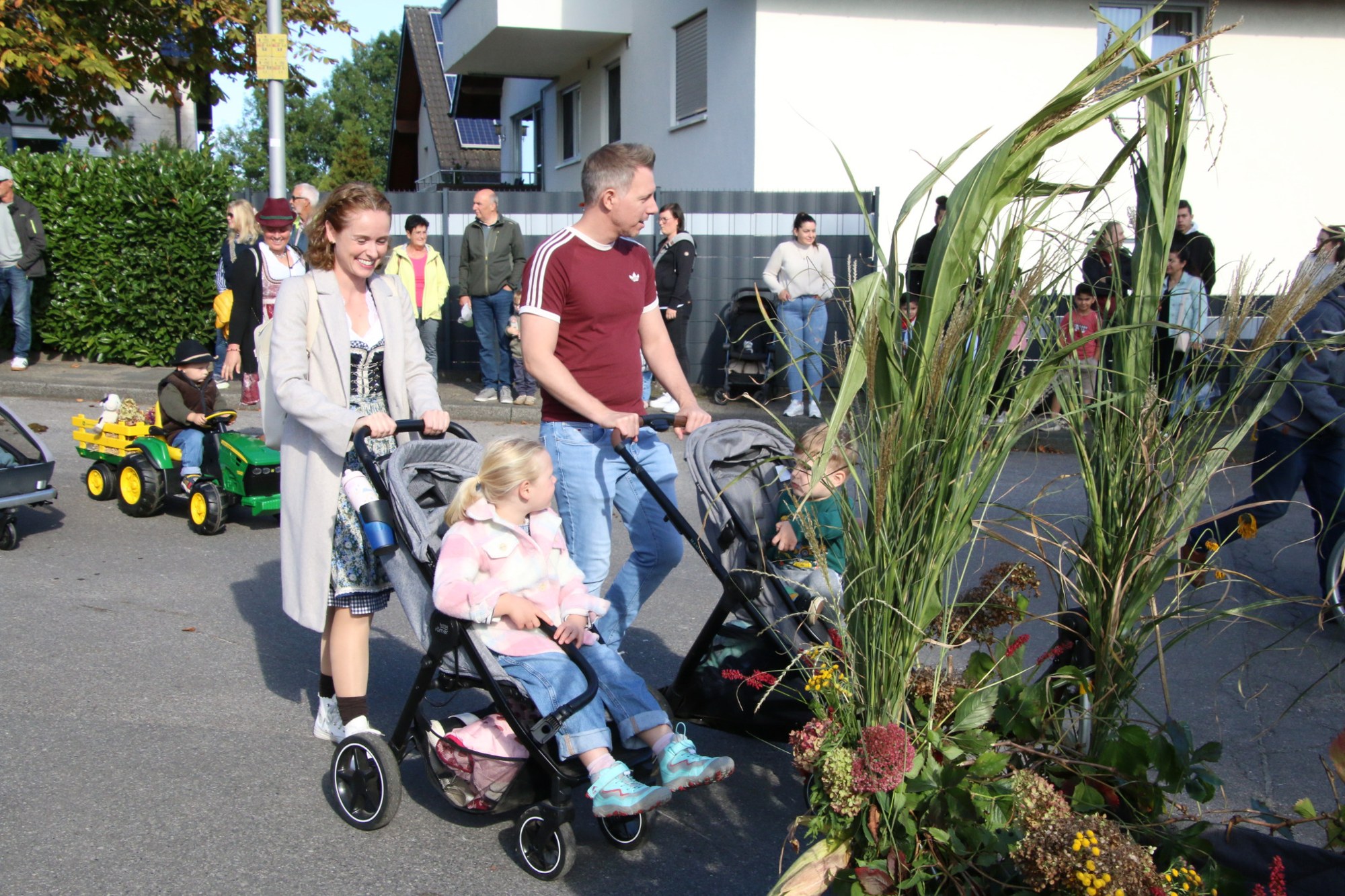 Familie mit Kinderwagen und Pflanzenschmuck beim Erntedankzug Walheim 2026.