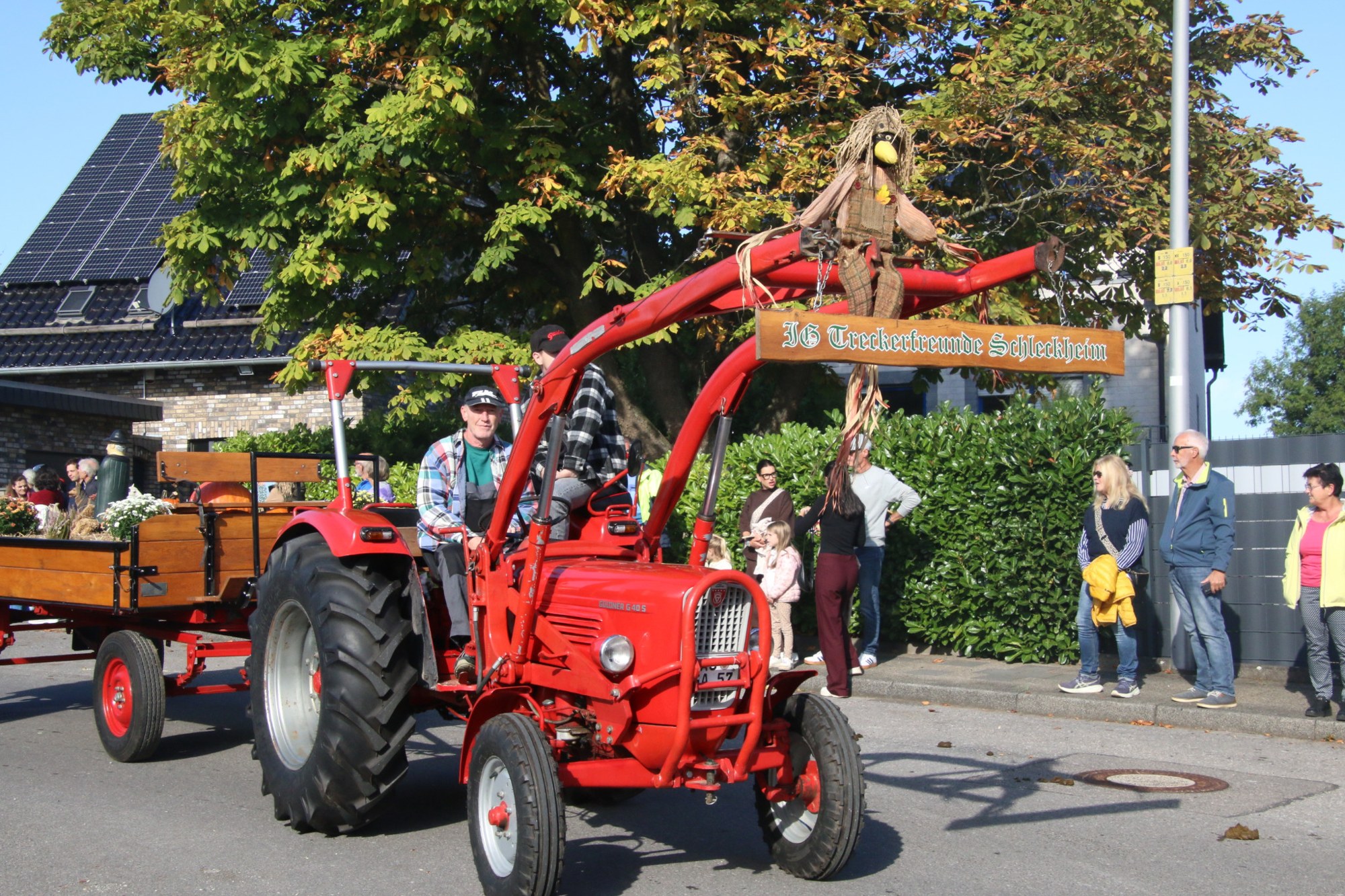 Roter Traktor mit erhobenem Frontlader beim Erntedankzug Walheim 2026.