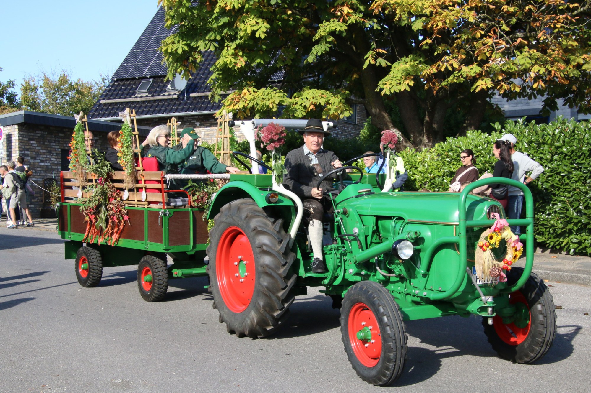 Grüner Traktor mit geschmücktem Anhänger beim Erntedankzug Walheim 2026.