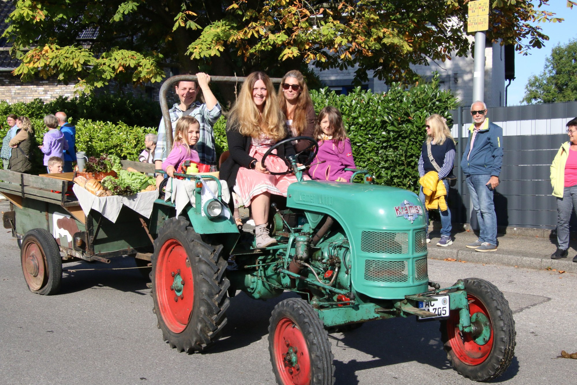 Familie auf einem kleinen grünen Traktor beim Erntedankzug Walheim 2026.