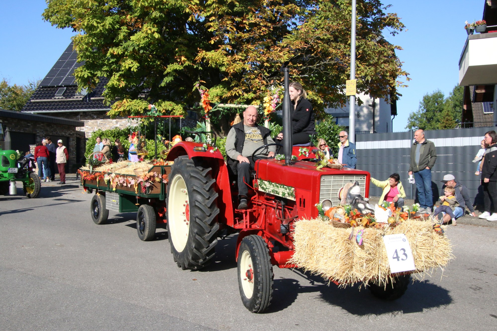 Roter Traktor mit Stroh- und Blumenschmuck beim Erntedankzug Walheim 2026.