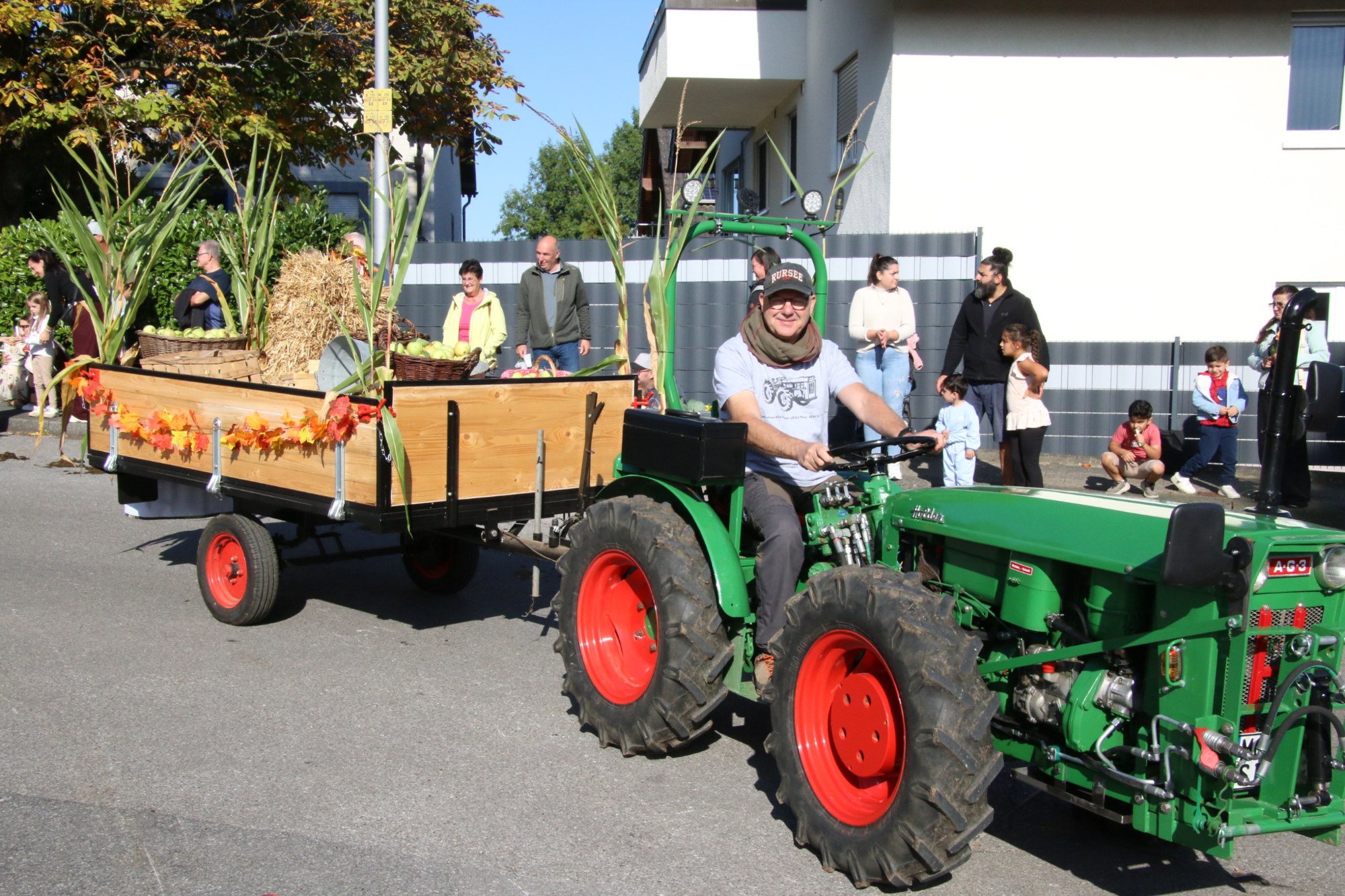 Grüner Traktor mit orangefarbenem Erntewagen beim Erntedankzug Walheim 2026.