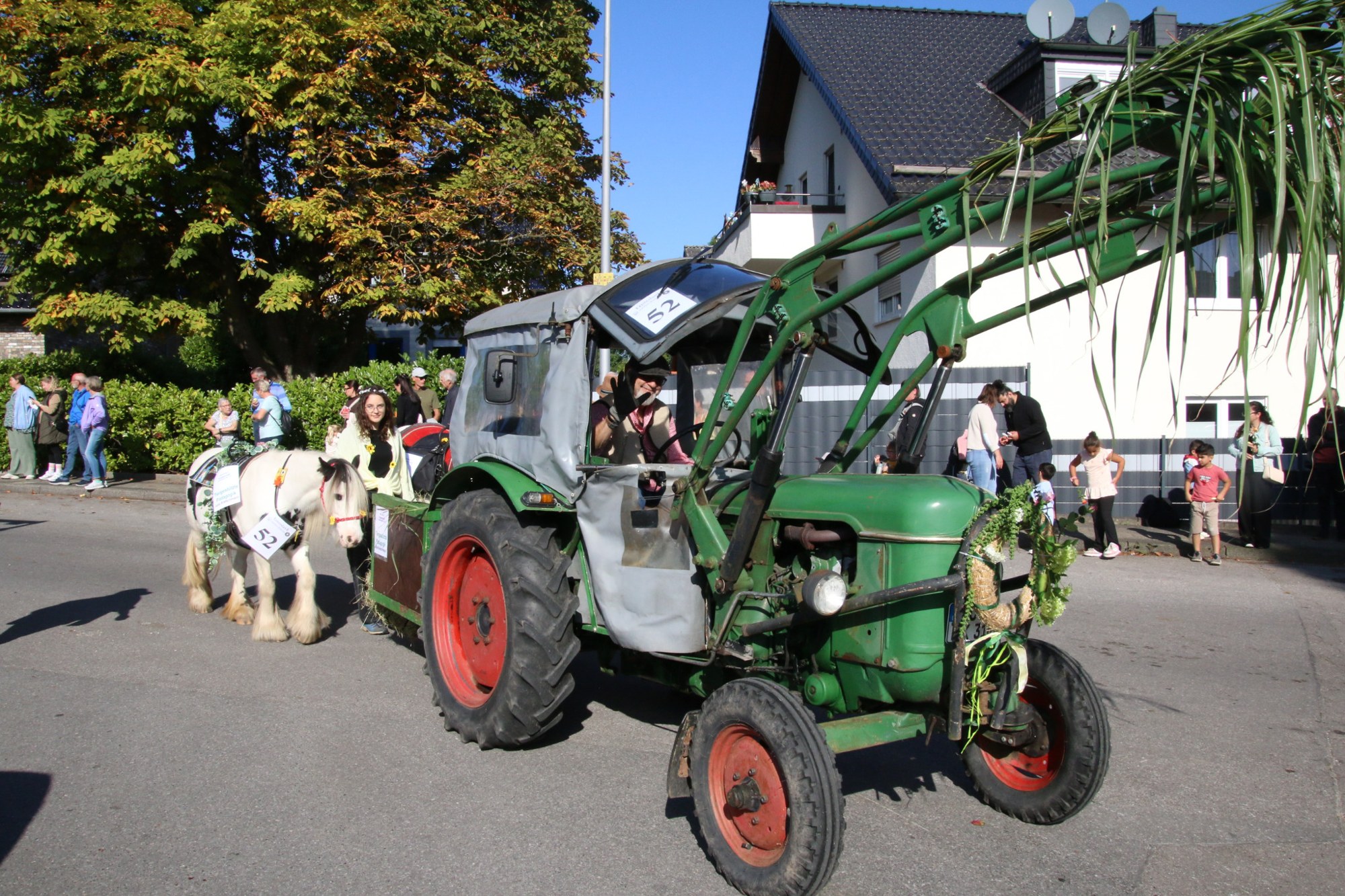 Grüner Traktor mit erhobenem Frontlader beim Erntedankzug Walheim 2026.