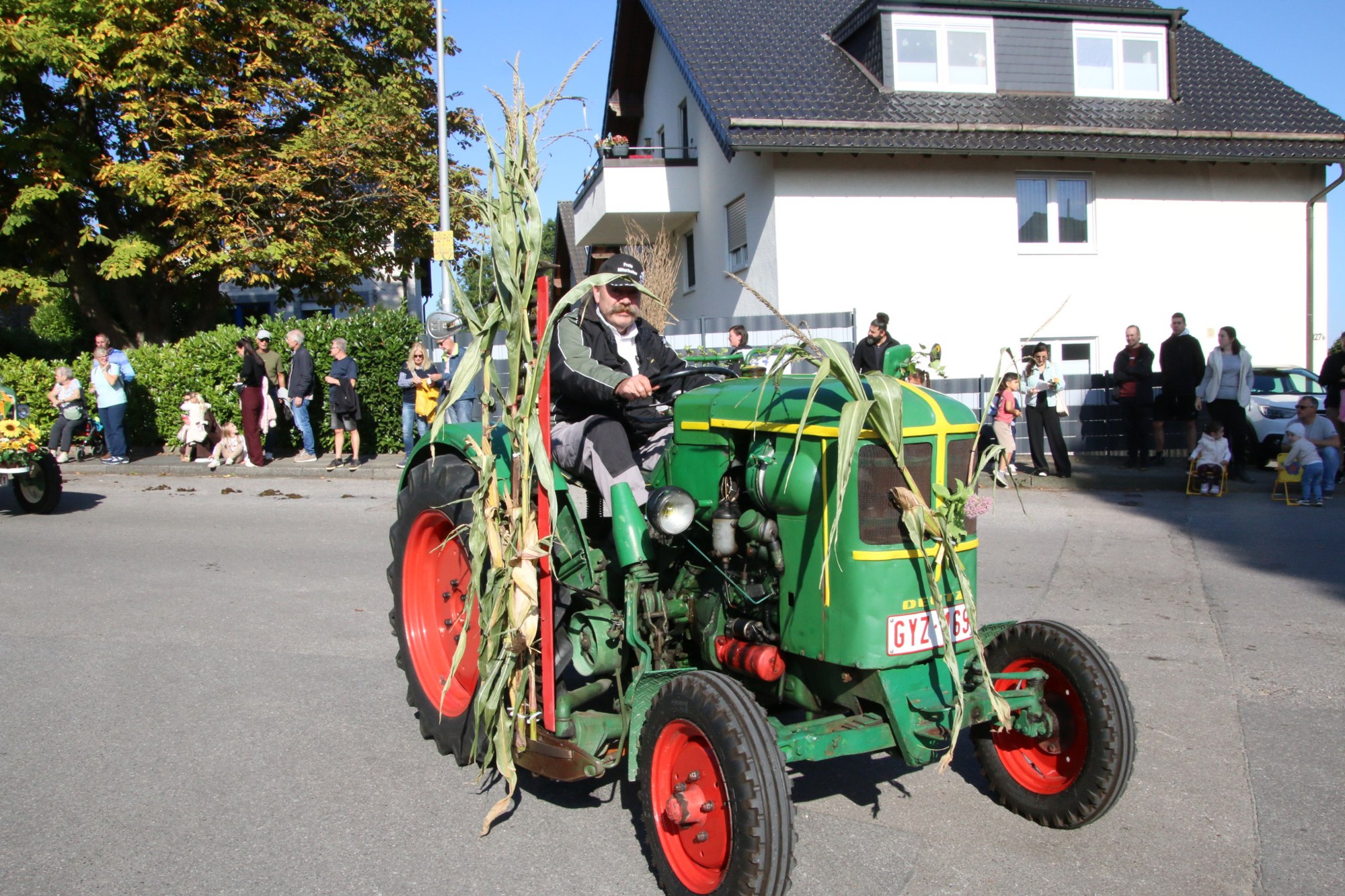 Grüner Oldtimertraktor mit Ernteschmuck beim Erntedankzug Walheim 2026.