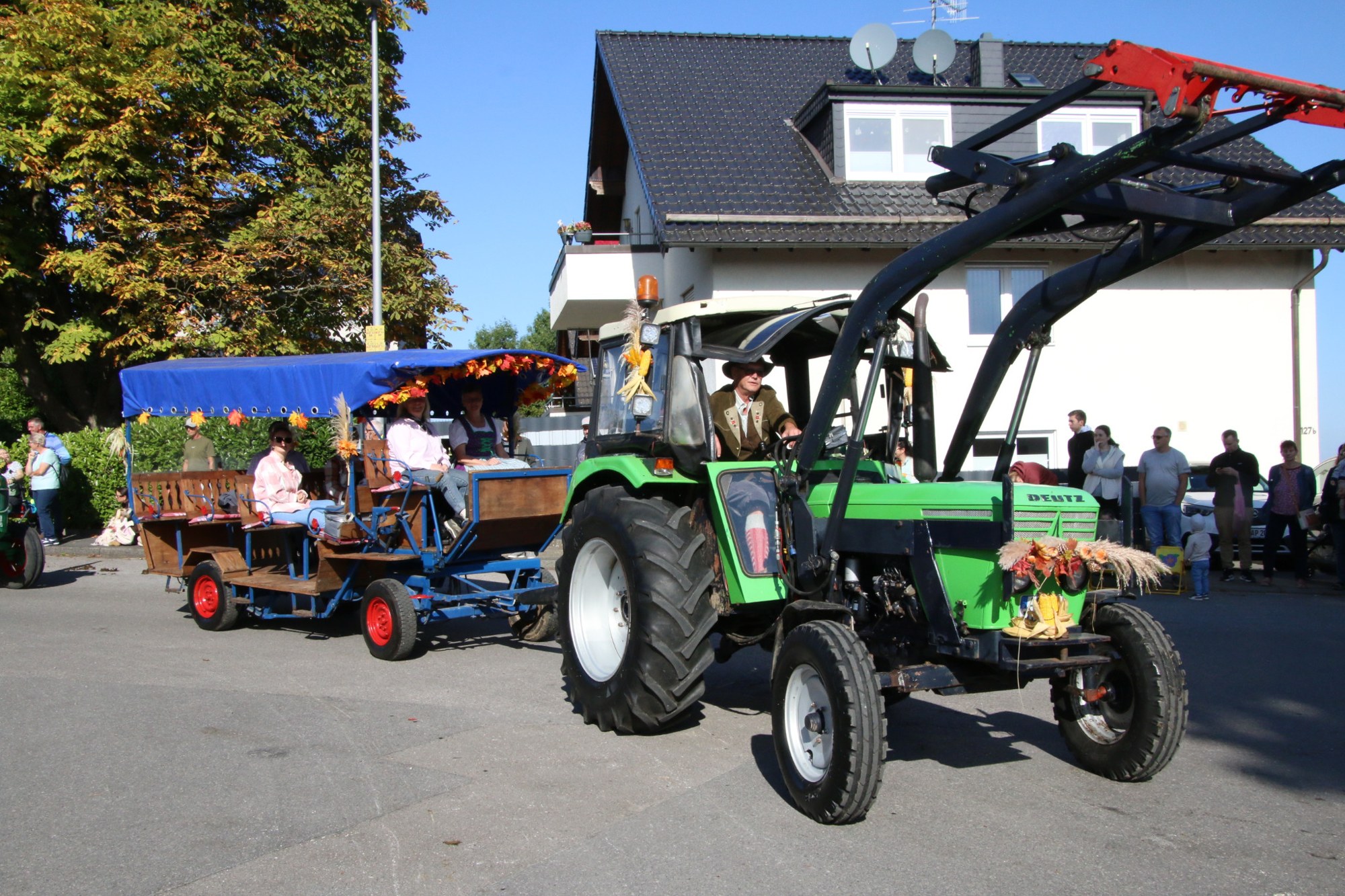Grüner Traktor mit Frontlader und Festwagen beim Erntedankzug Walheim 2026.