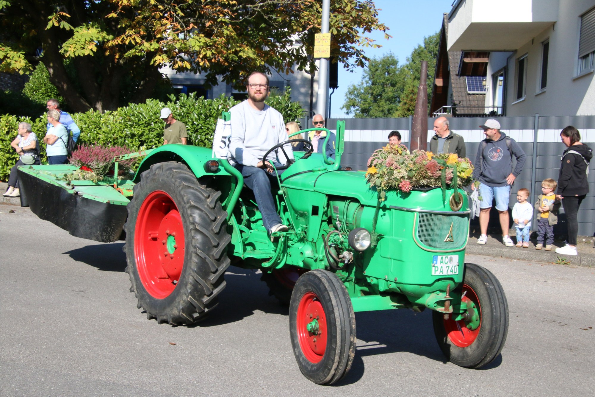 Grüner Oldtimertraktor mit Teilnehmern beim Erntedankzug Walheim 2026.