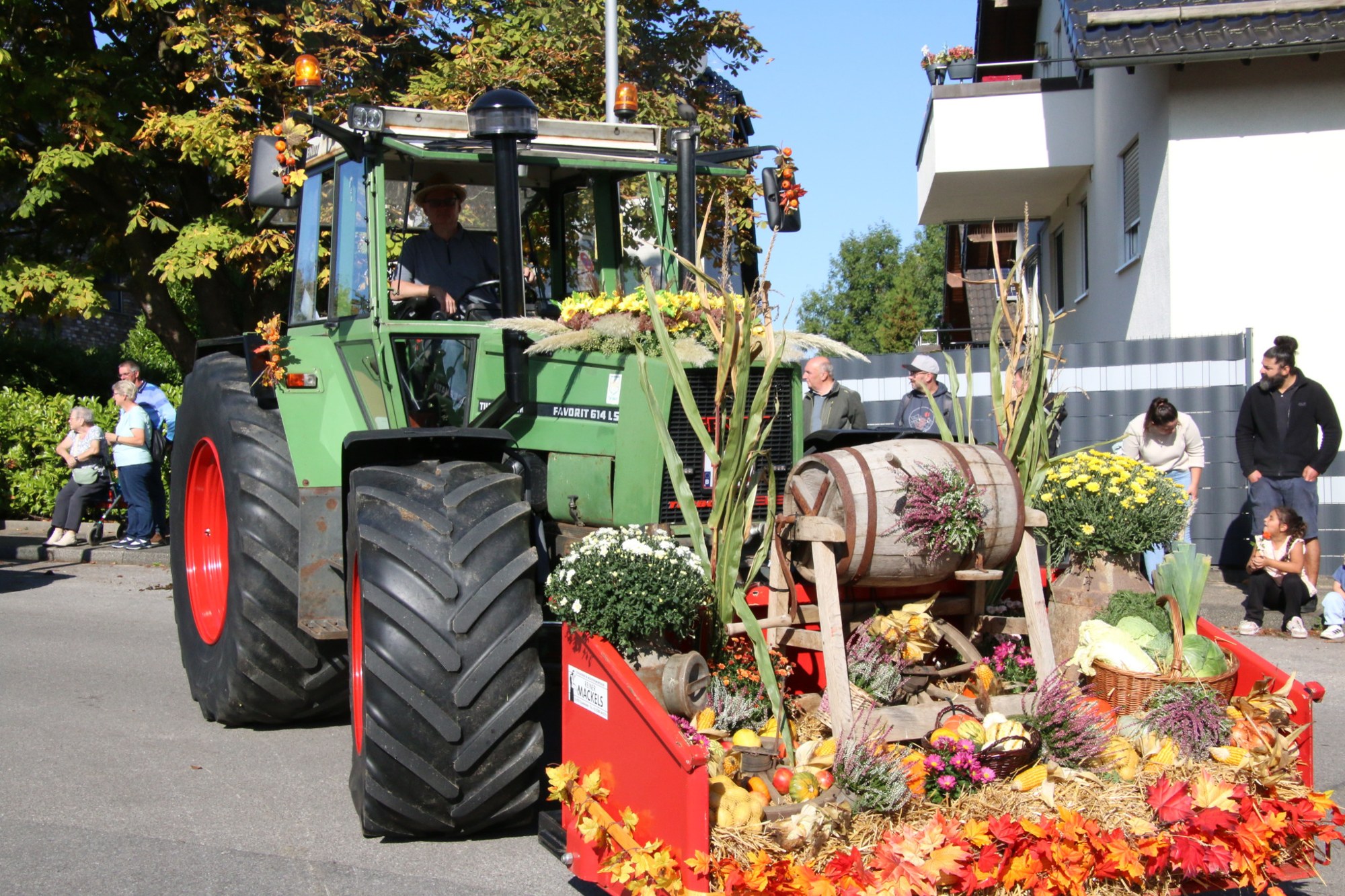 Grüner Traktor mit herbstlich geschmücktem Frontlader beim Erntedankzug Walheim 2026.