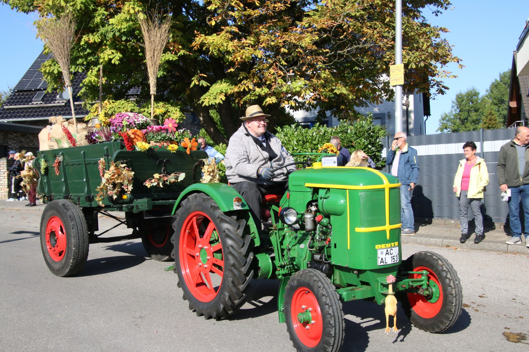 Grüner Traktor mit blumengeschmücktem Anhänger beim Erntedankzug Walheim 2026.