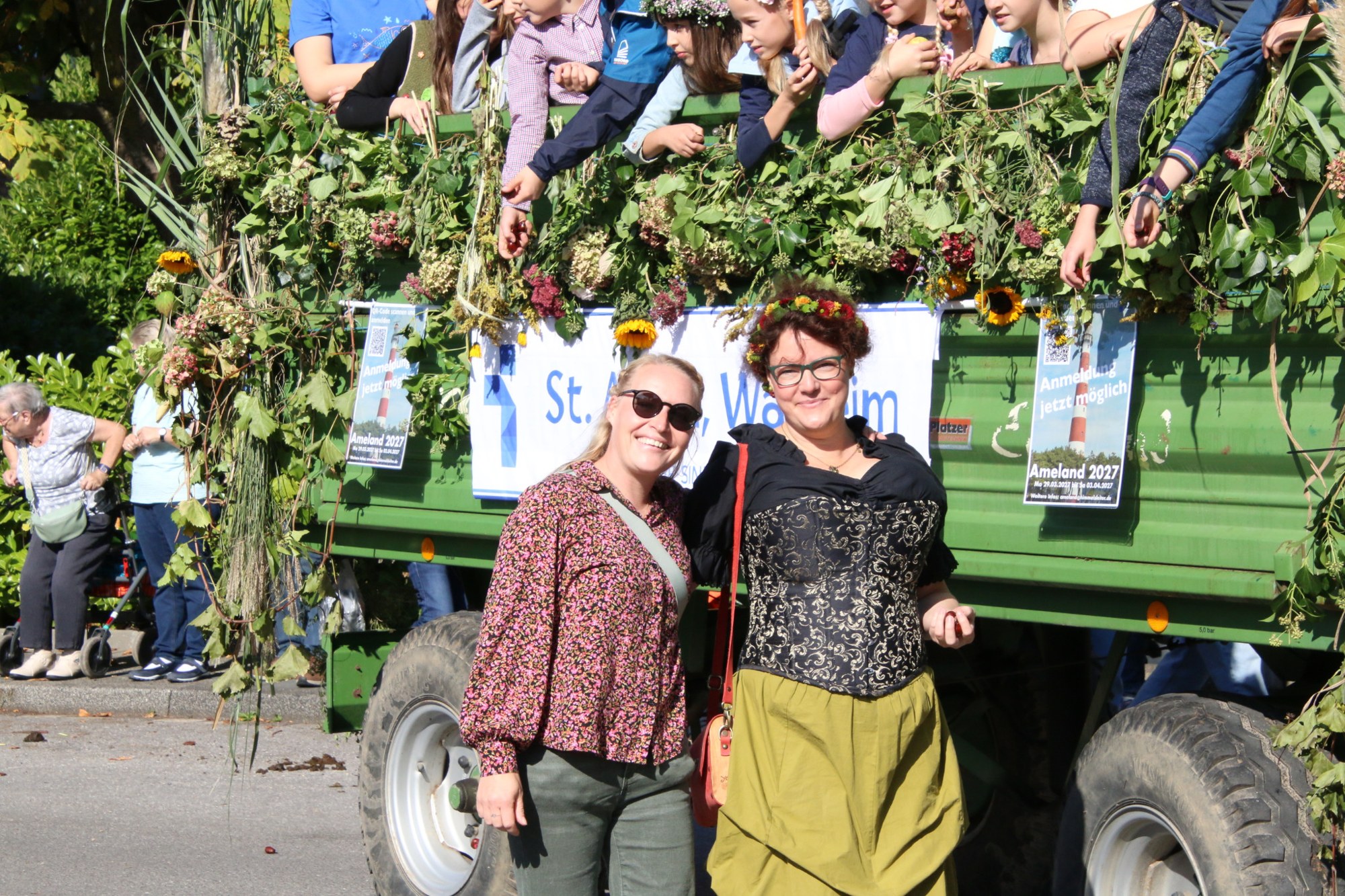 Teilnehmerinnen neben einem begrünten Festwagen beim Erntedankzug Walheim 2026.