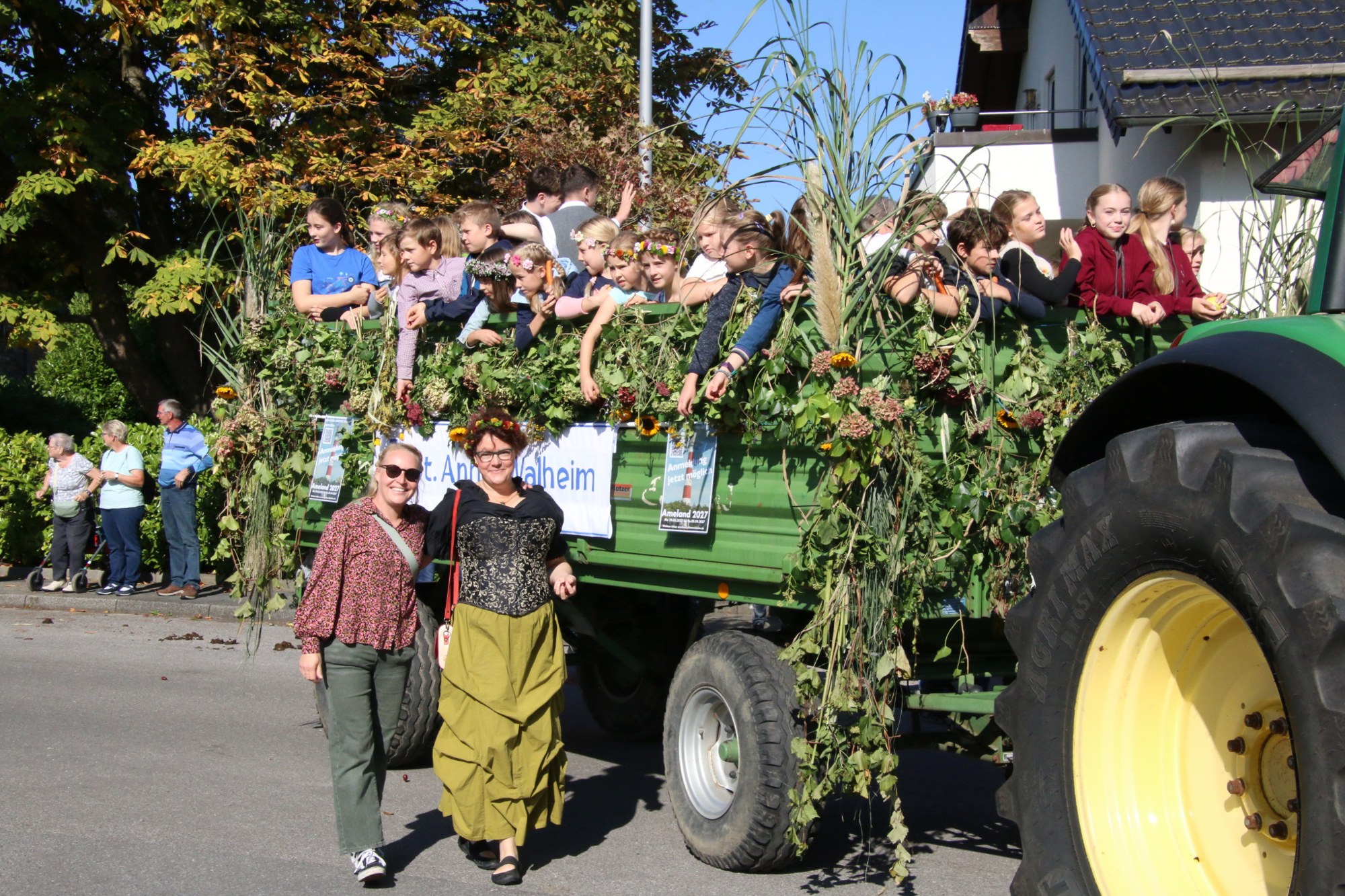 Grüner Traktor mit dicht geschmücktem Festwagen beim Erntedankzug Walheim 2026.
